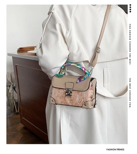 Detailed view of apricot box bag featuring floral lace texture and silk scarf handle