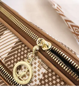 Macro detail of golden kangaroo logo zipper on premium plaid crossbody chest bag