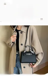 Nahaufnahme einer schwarzen Handtasche aus Narbenleder mit Seidenschal und Silberverschluss