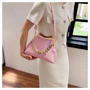 Detailed view of pink woven crossbody bag with gold chain and vintage metal clasp