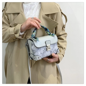 Close-up of vintage grey lace box bag with silk scarf handle and silver metal lock clasp