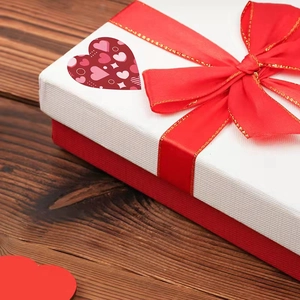 Rainbow heart Valentine's Day stickers on a white and red gift box with silk ribbon bow