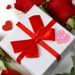 White gift box with red satin bow and rainbow heart sticker for Valentine's Day