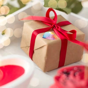 Rainbow heart sticker with geometric facets on kraft gift box with red ribbon
