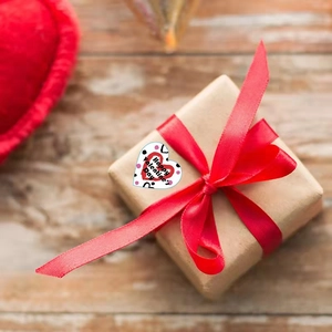 Heart-shaped Happy Valentine's Day sticker on a brown gift box with a red ribbon