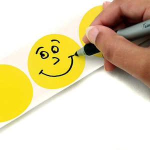 Close-up of handwriting on a 25mm yellow circular adhesive sticker with a black marker