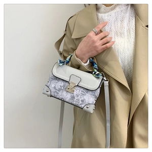 Detail of vintage embroidered box bag with silk scarf handle and silver hardware
