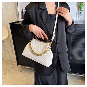 Detail of cream textured bag with gold chain, wood-style handle and metal clasp closure