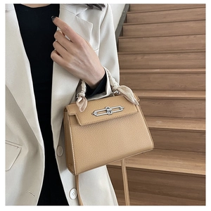 Detail der khakifarbenen Handtasche mit Litschi-Muster und seidenem Schal am Griff