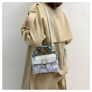 Detail of light blue box bag with white floral lace embroidery and silk scarf handle