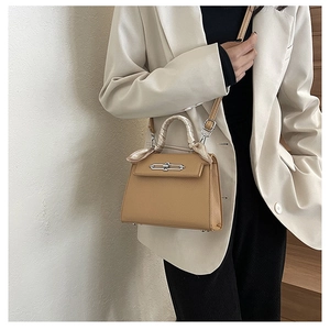 Nahaufnahme der Kelly-Tasche aus Leder mit dekorativem Seidentuch am Griff und Silberverschluss