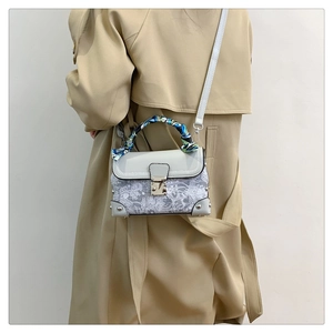 Detail of white lace box bag with silk scarf handle and silver metal lock hardware