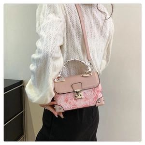 Detail of pink embroidered box bag with scarf handle on model in white knitwear