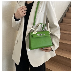 Detailansicht der grasgrünen Handtasche aus Leder mit dekorativem Seidenschal am Griff