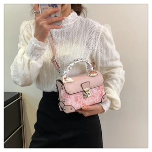 Detail of pink embroidered box bag with silk scarf handle and metal clasp closure