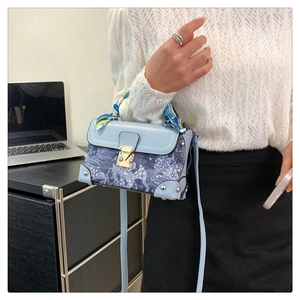 Detail of vintage floral embroidery box bag with silk scarf handle and gold buckle lock