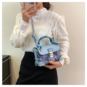 Detail of blue vintage embroidery bag with silk scarf handle and silver studs