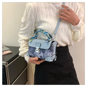 Detail of vintage box bag featuring floral embroidery, silk scarf handle, and metal lock