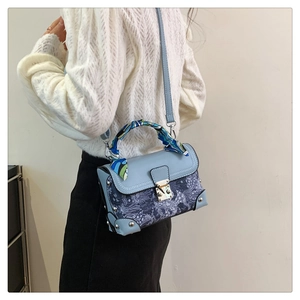 Close-up of vintage embroidery box bag featuring silk scarf handle and metal lock
