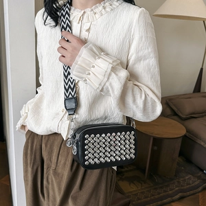 Fashionable black crossbody bag with rhinestones and wide chevron strap on model