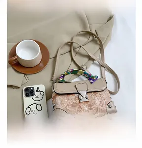 Detail of vintage beige box bag with floral embroidery texture and silk scarf handle
