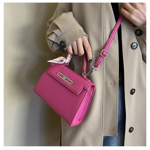 Detail der rosaroten Kelly-Tasche aus Leder mit gebundenem Seidentuch und Metallschloss