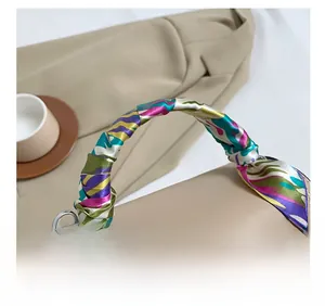 Detail of elegant beige handbag with silk scarf wrapped handle and silver metal hardware