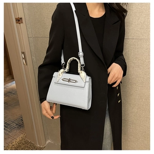 Detail der hellblauen Lederhandtasche mit elegantem Seidenschal am Tragegriff