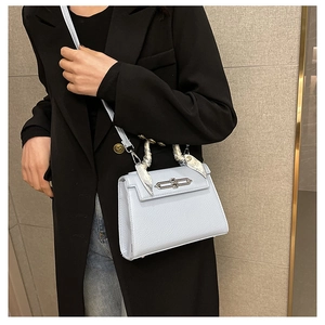 Hellblaue Kelly-Tasche aus Leder mit Seidentuch am Griff, getragen von einem Model
