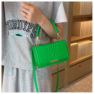 Close-up of bright green quilted handbag with woven handle and elegant metal trim