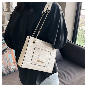 Détail du sac blanc à motif crocodile avec logo doré et bandoulière en chaîne