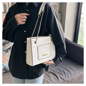 Détail du sac cabas blanc à motif crocodile avec chaîne dorée et logo en métal gravé