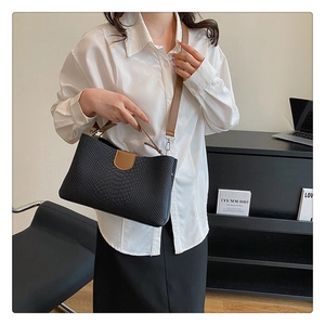 Detail of black crocodile texture tote bag with brown leather strap and magnetic closure