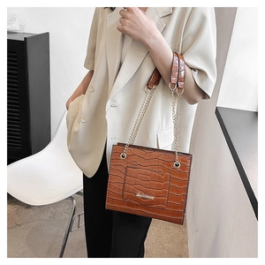 Détail du sac bandoulière marron motif crocodile avec chaîne dorée et logo en métal