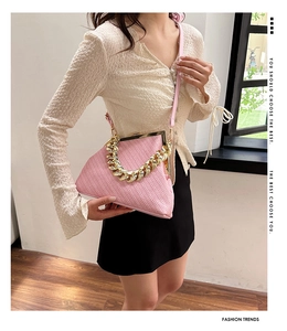 Detail of pink woven texture shell bag with chunky gold chain strap and metal clasp