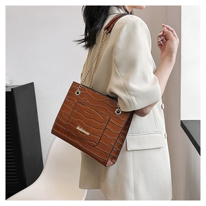 Détail du sac à bandoulière marron foncé texture crocodile avec chaîne dorée élégante