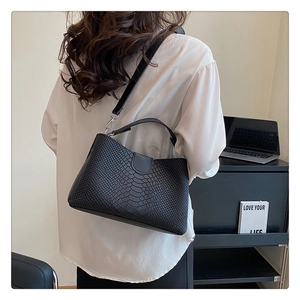 Close-up of black PU handbag showing embossed snakeskin texture and metal hardware