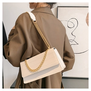 Détail d'un sac bandoulière beige à motif pierre avec chaîne dorée sur un mannequin