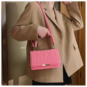 Detail of pink quilted handbag showing V-shaped stitching and golden metal hardware