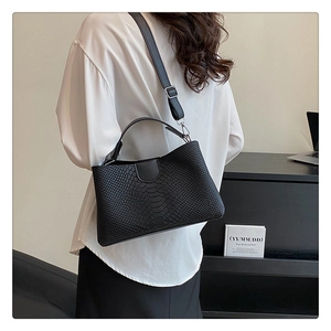 Close-up of black PU leather shoulder bag with crocodile texture worn by a model