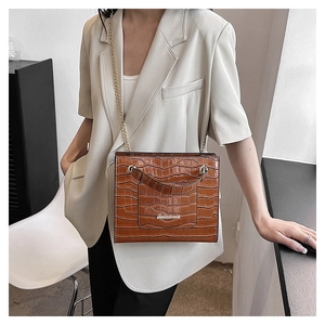 Détail d'un sac bandoulière marron aspect croco avec chaîne dorée et logo de marque