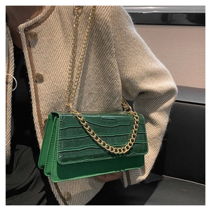 Détail du sac à main vert à motif crocodile avec une bandoulière à chaîne dorée