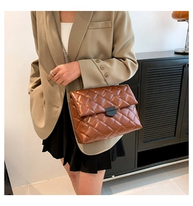 Nahaufnahme einer braunen Stepptasche mit Kette, getragen zum khakifarbenen Blazer
