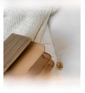 Détail du sac à bandoulière beige avec motif crocodile et chaîne dorée élégante