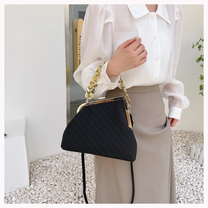 Detailed view of black striped shell bag featuring a thick gold chain and clip frame closure