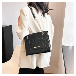 Détail du sac noir à motif crocodile avec chaîne dorée et logo de la marque