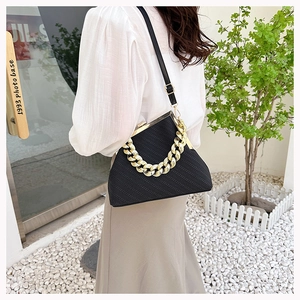 Fashionable black shell bag with striped texture and gold chain worn by a model