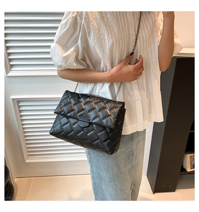 Schwarze Stepptasche mit dunkelgrauer Metallkette, getragen von einem Modell