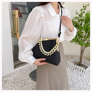 Detail of black textured shell bag with chunky gold chain and retro clasp closure
