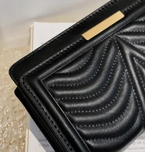 Close-up of black quilted leather with V-shaped stitching and golden metal hardware